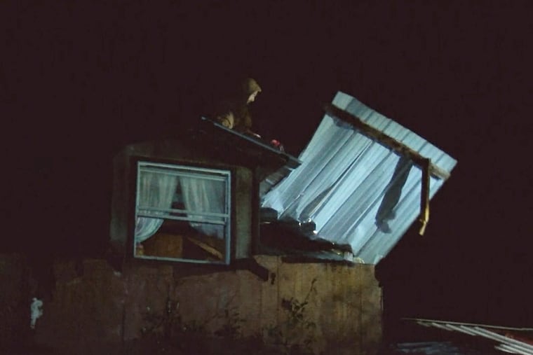 An emergency worker moves debris on top of a damaged house early Wednesday in Caddo Parish, La.