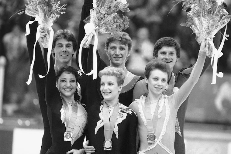 Soviet figure skaters Elena Valova and Oleg Vasiliev, who won Olympic gold, are flanked by Kitty and Peter Carruthers, left, who grabbed silver, and Soviet pair Larisa Selezneva and Oleg Makarov, bronze, as they wove mimosa bunches to the cheering crowd, Feb. 12, 1984, at Sarajevo, Yugoslavia.