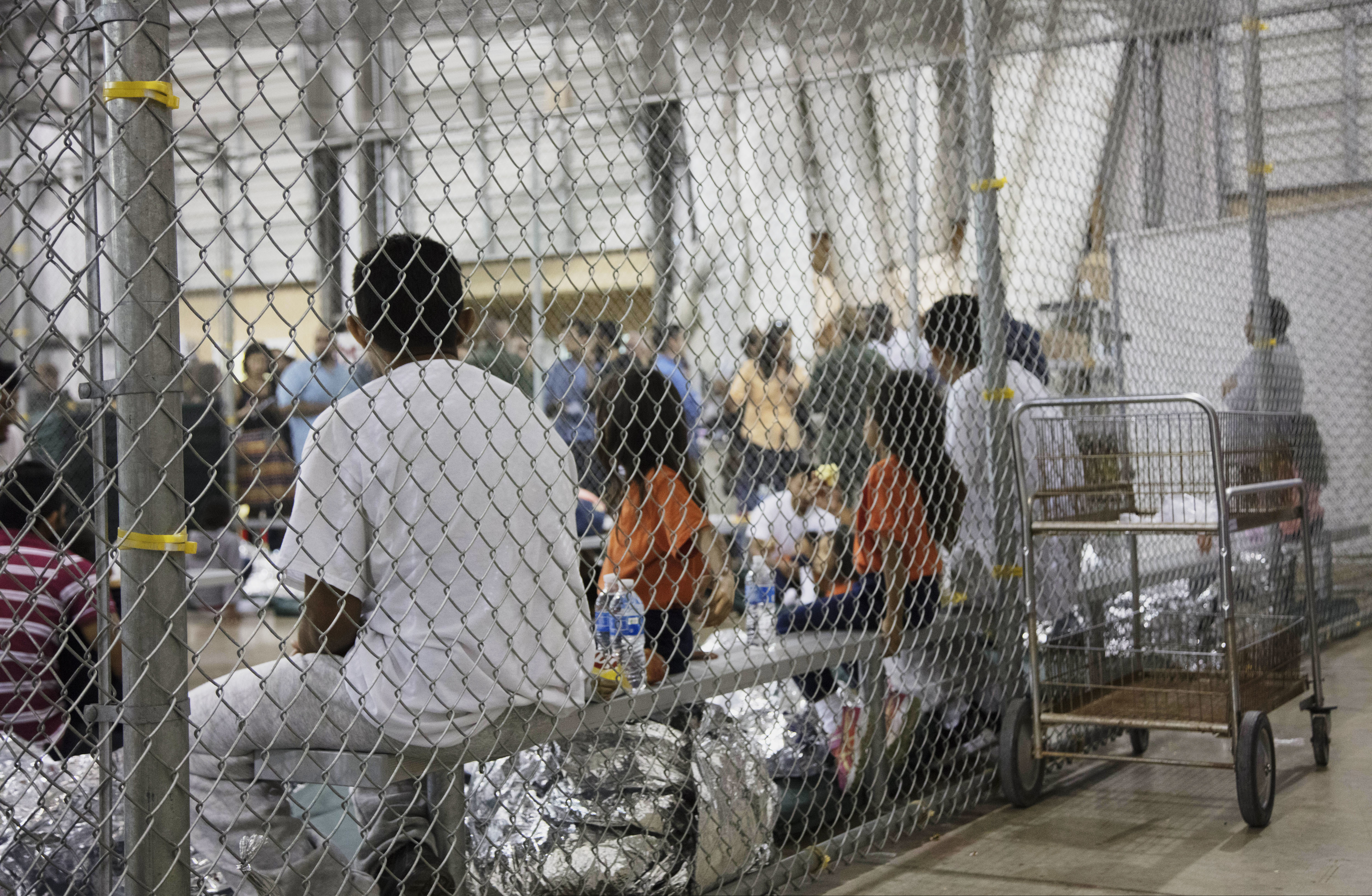 FILE - In this June 17, 2018, file photo, provided by U.S. Customs and Border Protection, people who have been taken into custody related to cases of illegal entry into the United States, sit in one of the cages at a facility in McAllen, Texas. Advocates were shocked to find an underage mom and her tiny, premature newborn daughter huddled in a Border Patrol facility this week in what they say was another example of the poor treatment immigrant families receive after crossing the border. The mother is a Guatemalan teen who crossed the border without a parent and was held at a facility in McAllen, Texas.