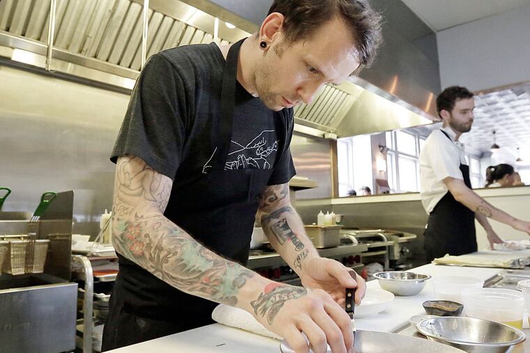 Aldine chef/owner George Sabatino plates the cotechino sausage with tomato and garlic sauce and charred garlic scapes at the restaurant. ( ELIZABETH ROBERTSON / Staff Photographer )