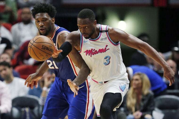 Heat guard Dwyane Wade (3) and 76ers center Joel Embiid battliing for the ball during the second half.