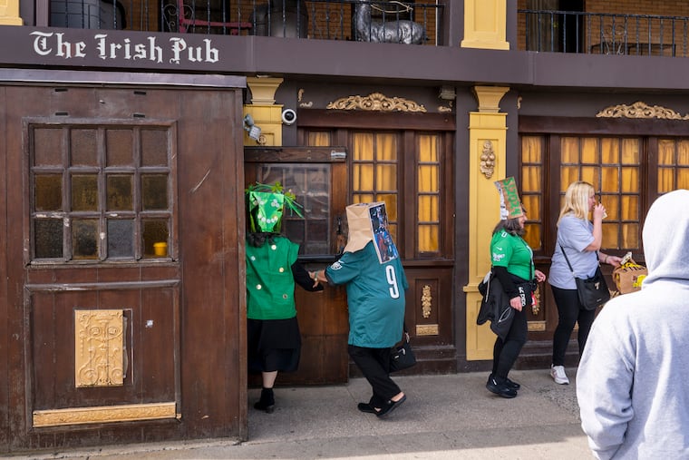 Fran Cann (left) helps Debbie Stiles get through the door at the Irish Pub. The friends from Berlin, N.J., were celebrating Bag Day at the Irish Pub in Atlantic City in 2024. The tradition got started when a late-to-the-party patron showed up at the 24-hour bar a day after St. Patrick's Day, then put a bag on their head.