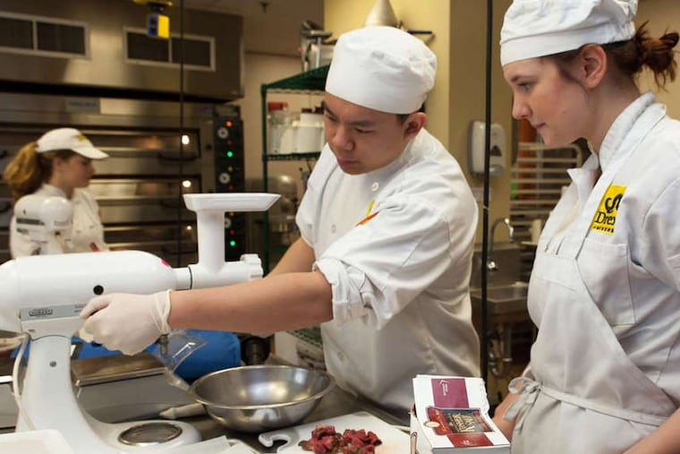 Drexel University culinary students Greg Ng and Erica Ewwefsen (right) prepare a meat dish in the Drexel Food Lab during Drexel's Chef Conference Friday, January 23, 2015. (Chanda Jones / Staff Photographer)