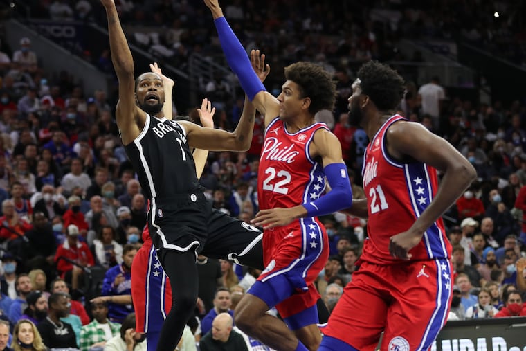 Kevin Durant, left, of the Nets shoots against Matisse Thybulle, center, and Joel Embiid, right, of the Sixers during the second half of the Sixers' home opener at the Wells Fargo Center.