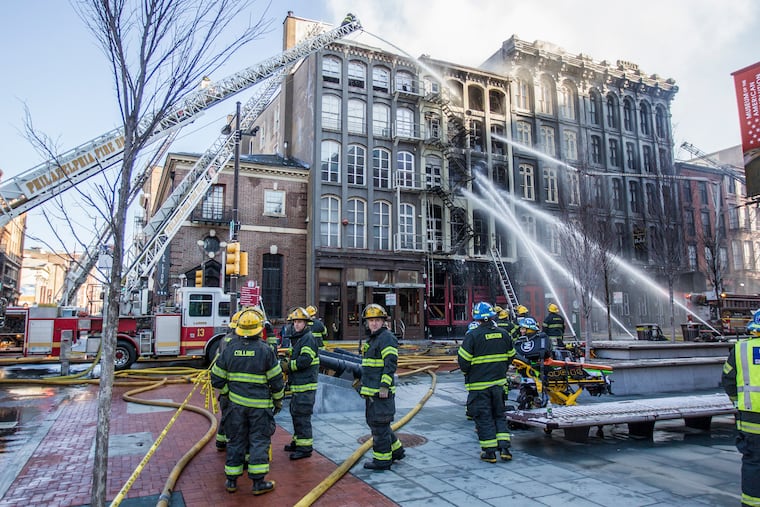 Philadelphia Firefighters watch as water is poured onto the 200 block of Chestnut Street in February 2018. City Council is considering legislation that would require sprinkler systems in more apartment buildings.
