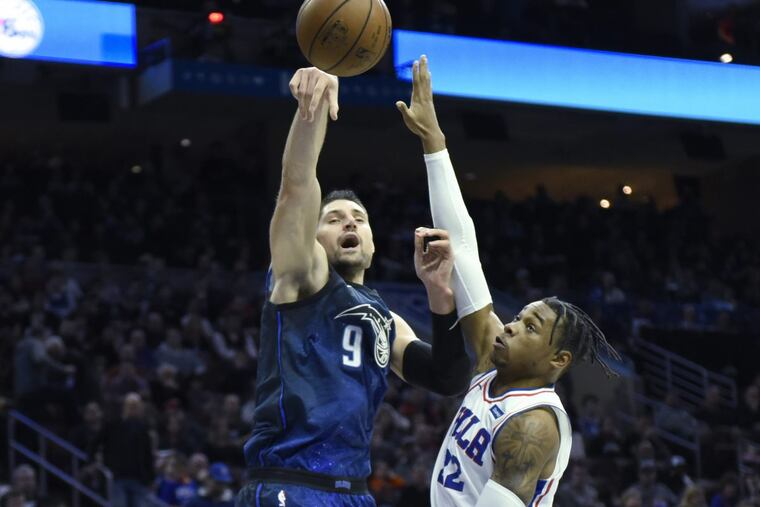 Sixers big man Richaun Holmes contests Magic center Nikola Vucevic, a former Sixer, during Philadelphia’s win on Saturday.