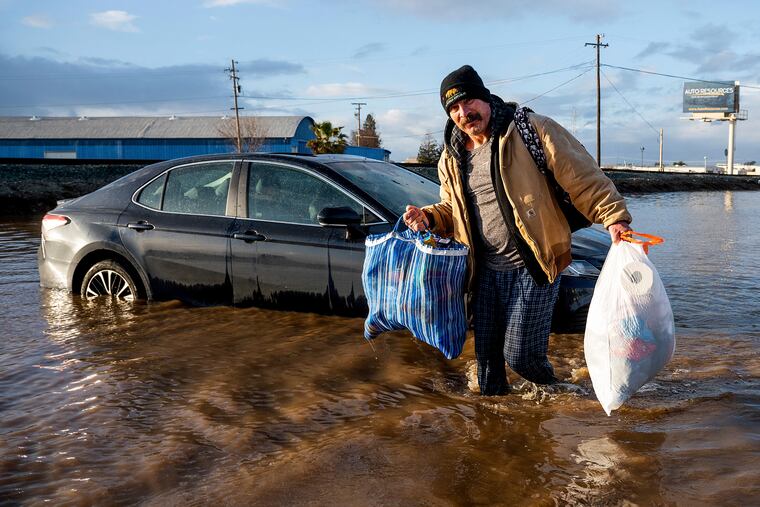Jesus Torres carries belongings from his flooded Merced, Calif., home on Tuesday, Jan. 10, 2023.