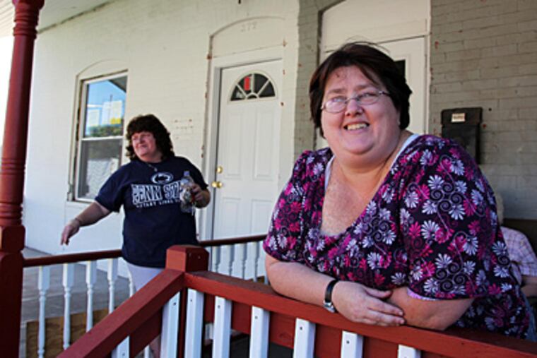 Geneva Thomas, right, and her neighbor, Jane Hickman, pose Saturday on the front porch of Hickman's home on the 300 block of Fleetwood Street in
Coatesville. The block was burned by arson earlier in the year. (Laurence Kesterson / Staff Photographer)
