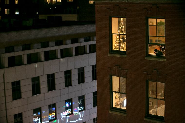 Anna Evenosky, 22, looks out of her apartment window on Walnut Street after hearing a fire alarm. A first-year grad student working toward her doctorate in physical therapy, Evenosky was home because she had just learned she was exposed to COVID-19 by a lab partner and needed to quarantine for 14 days. Evenosky wrote in a text that she put up a Christmas tree on Nov. 7 because she needed something to raise her spirits amid the stress of the election, the pandemic, and grad school, but that she was trying to stay positive.
