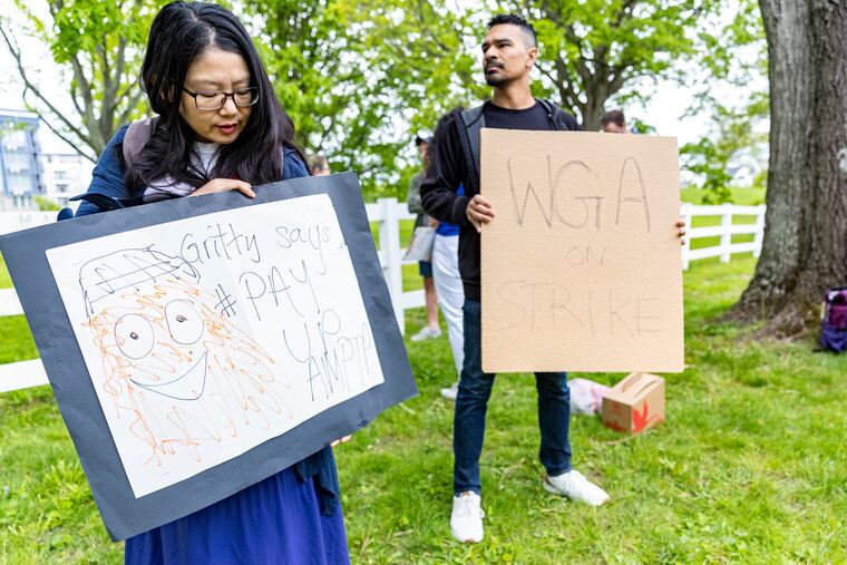 Shuo Zhang (left), of Newtown Square and a member of the WGA, and Ramon Jackson, of Center City Philadelphia, a staff representative with SAG-AFTRA, hold picket signs. They were picketing with WGA members at the production of the Apple TV+ series “Sinking Spring” in Newtown Square, Pa., on Tuesday, May 9, 2023.