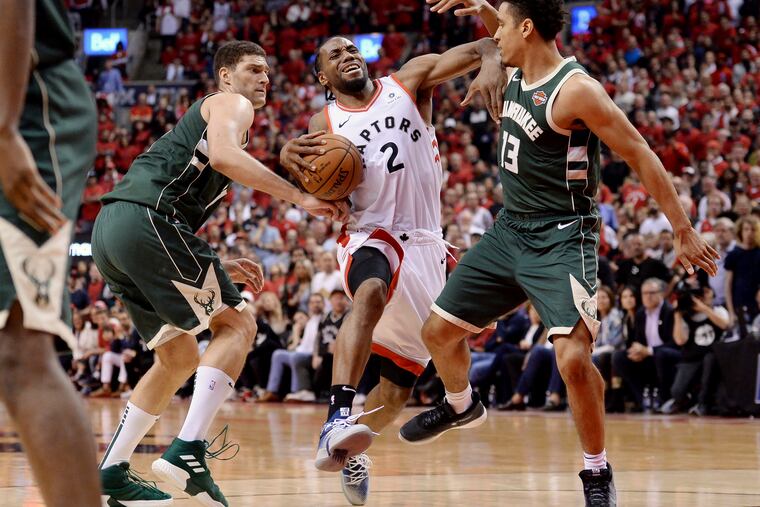 Kawhi Leonard drives to the basket against Milwaukee's Brook Lopez (right) and Malcolm Brogdon during the second overtime of Game 3 on Sunday.