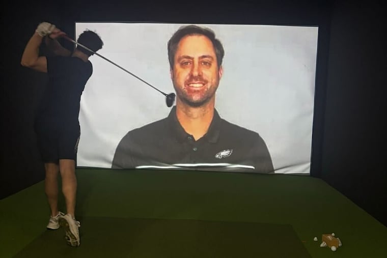 An Eagles fan hits a golf ball at an image of Eagles offensive coordinator Kevin Patullo at The Golf Place in Langhorne.