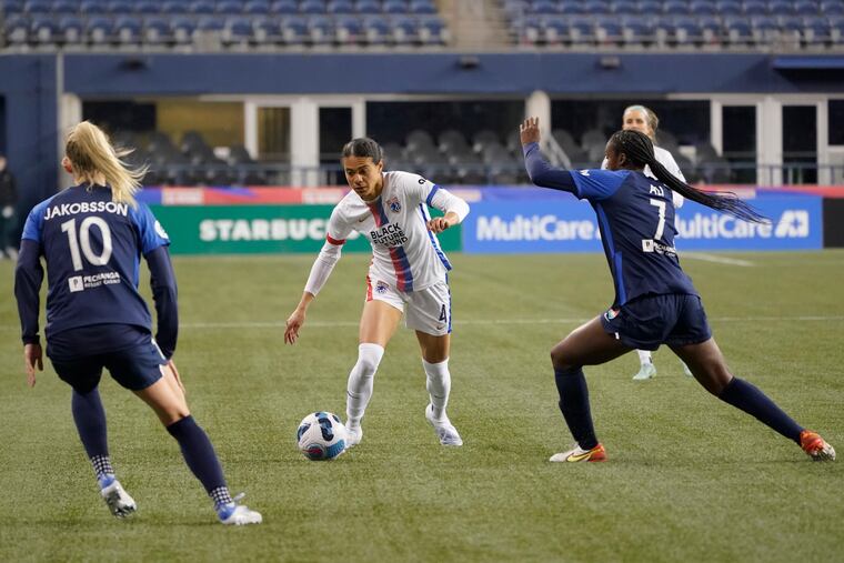 OL Reign defender Alana Cook maneuvers between San Diego Wave forwards Sofia Jakobsson and Amirah Ali in April.