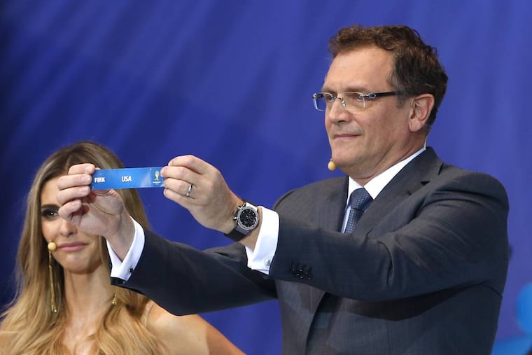 FIFA Secretary General Jerome Valcke shows the ticket of USA during the draw ceremony for the 2014 soccer World Cup in Costa do Sauipe near Salvador, Brazil, Friday, Dec. 6, 2013. (AP Photo/Andre Penner)