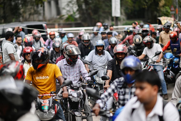 Motorists queue up as others wait behind a rope for their turn to get fuel at a pump, fearing a possible fuel shortage due to the Iran war, in Dhaka, Bangladesh, Sunday, March 8, 2026.