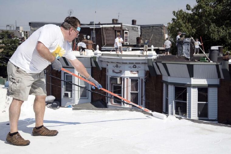 Energy Coordinating Agency volunteers apply roof coatings to North Philadelphia row houses in July 2016. ECA’s founder and executive director, Liz Robinson, announced Monday she is stepping down in August.