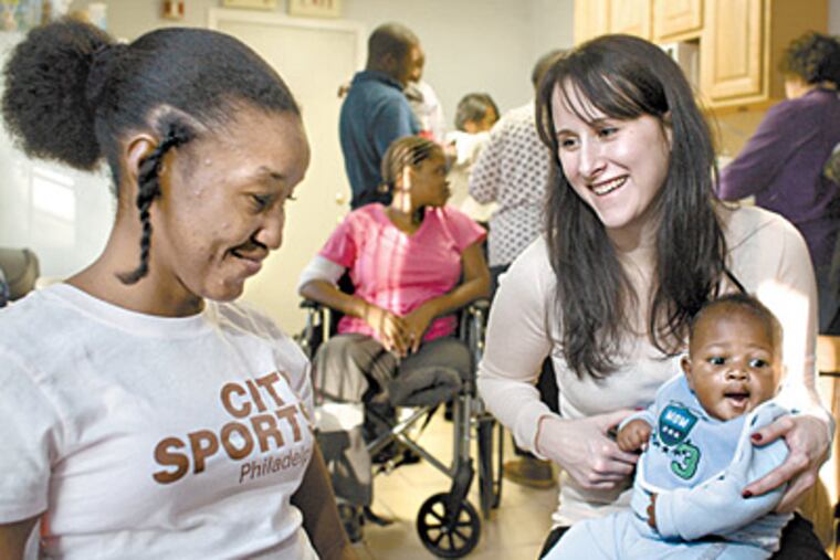 Penn medical student Naomi Rosenberg (right) talks to Celine Gay while balancing 3-month-old Harvell on her knee. Both Haitians came to Philadelphia for medical treatment. (Ed Hille / Staff)