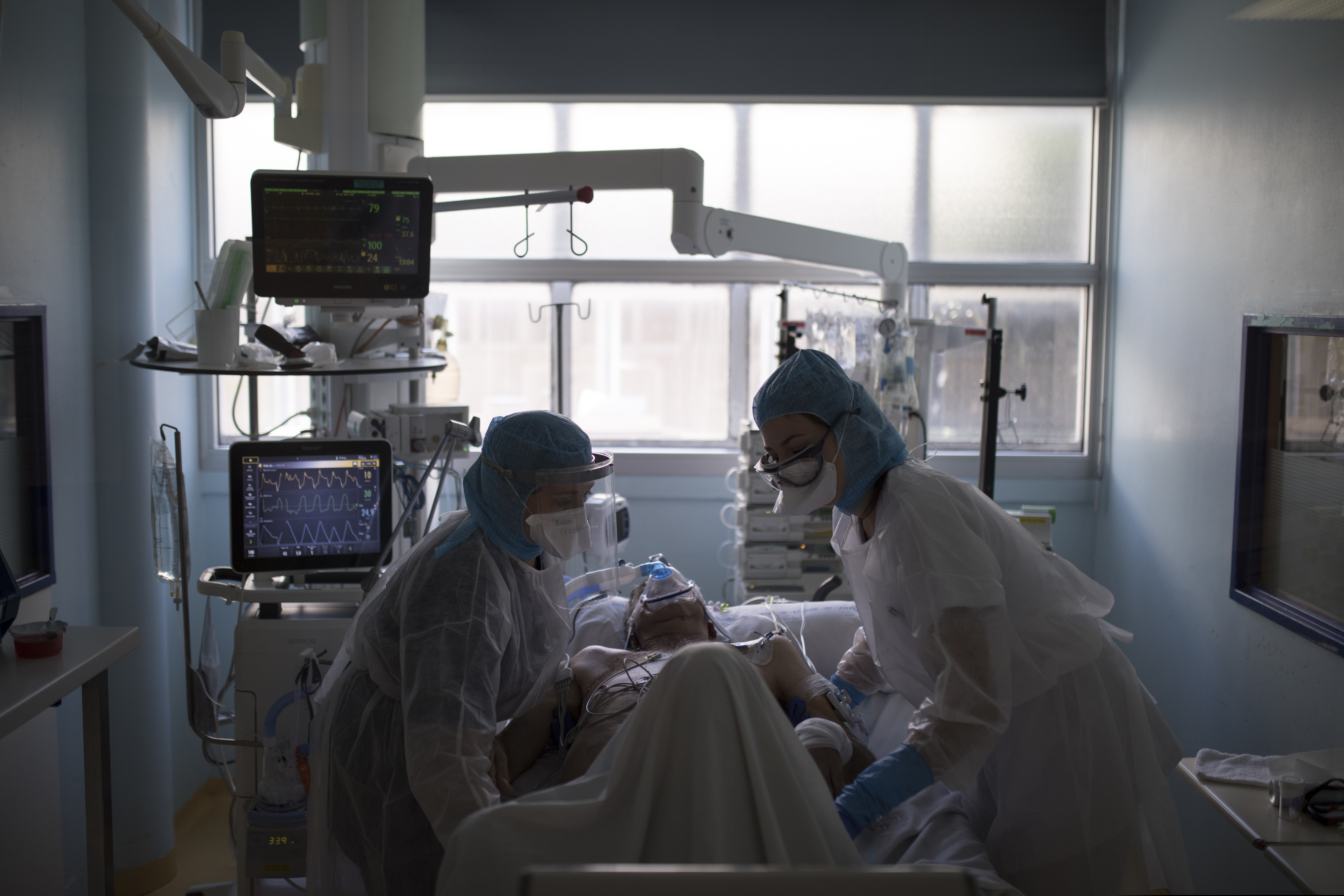 Healthcare workers assist a COVID-19 patient in the intensive care unit at the Joseph Imbert Hospital Center in Arles, southern France, Wednesday, April 15, 2020.