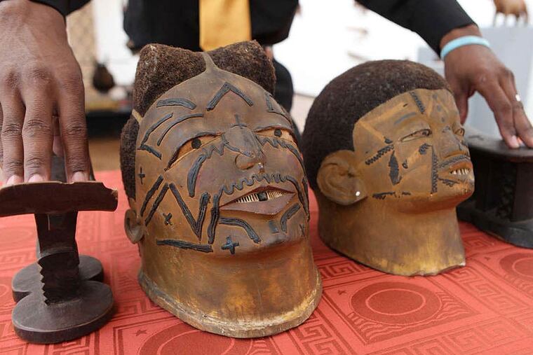 At the National Art Gallery in Harare, Zimbabwe, a worker shows some of the returned artifacts, including tribal face masks and headrests. (TSVANGIRAYI MUKWAZHI/AP)