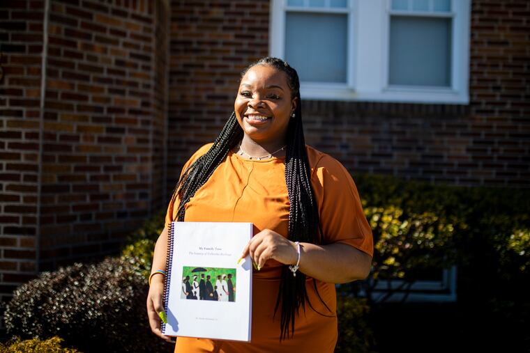 Tulleesha Burbage, 26, of Upper Darby, holds the genealogy book made by her friend Dennis Richmond, Jr.