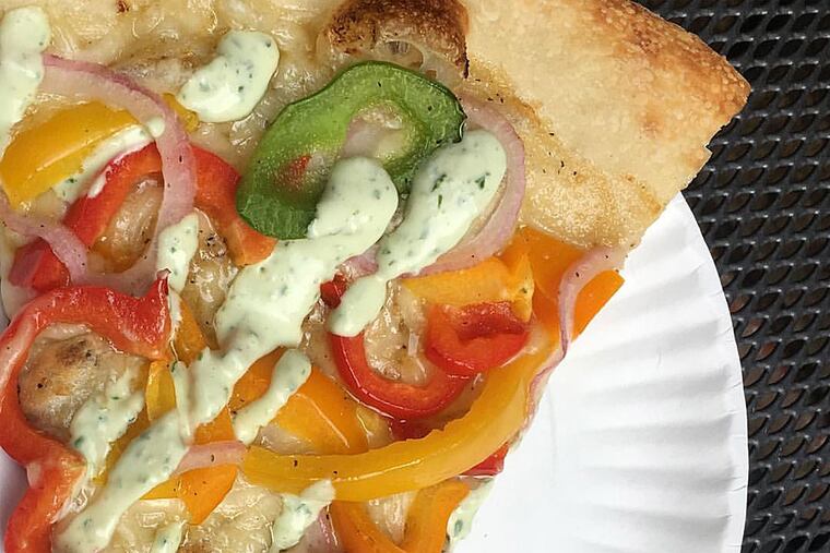 A slice of garlic butter, violife, peppers, cracked black pepper, red onions, and ranch dressing, served at Blackbird Pizzeria.