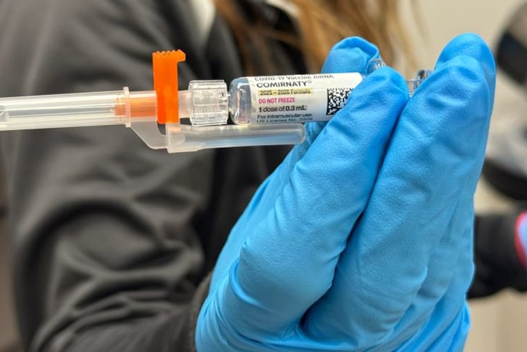 A pharmacy employee holds a vial of the updated COVID-19 vaccine made by Pfizer.