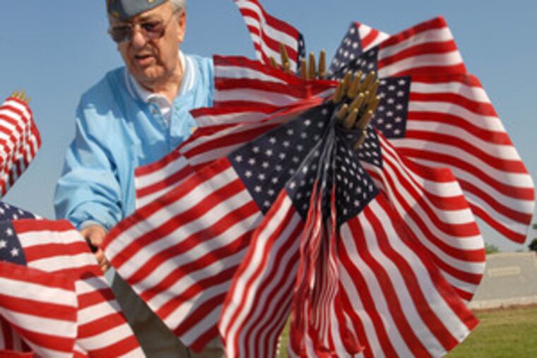 Gus DiMino places flags for Memorial Day on the graves of veterans in St. Patrick's Catholic Cemetery in Norristown.