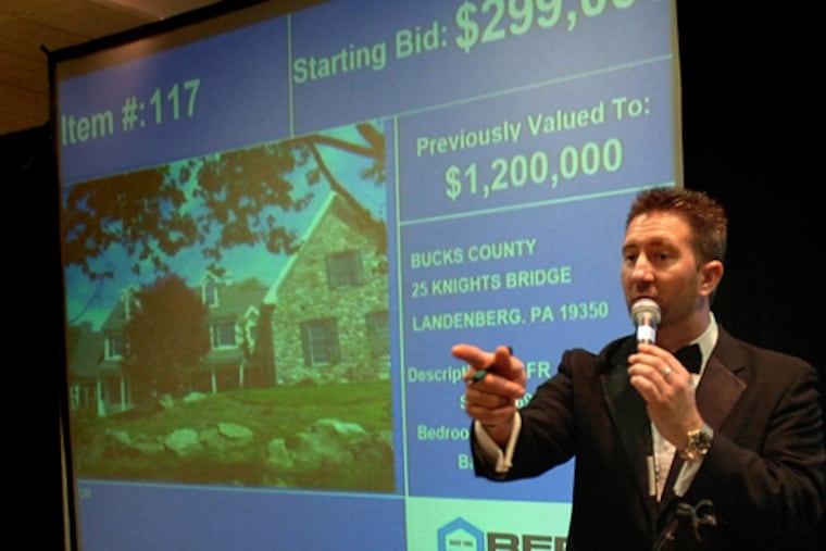 Auctioneer Mike Carr, at the Valley Forge sale, fields bids forthe home on the screen. A couple won with the highest offer: just $495,000 for the million-dollar-plus property.