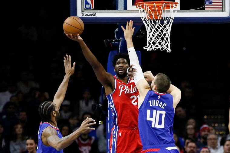 Sixers center Joel Embiid goes up for a shot between the Clippers' Ivica Zubac (right) and Kawhi Leonard during the first half of Tuesday's game.