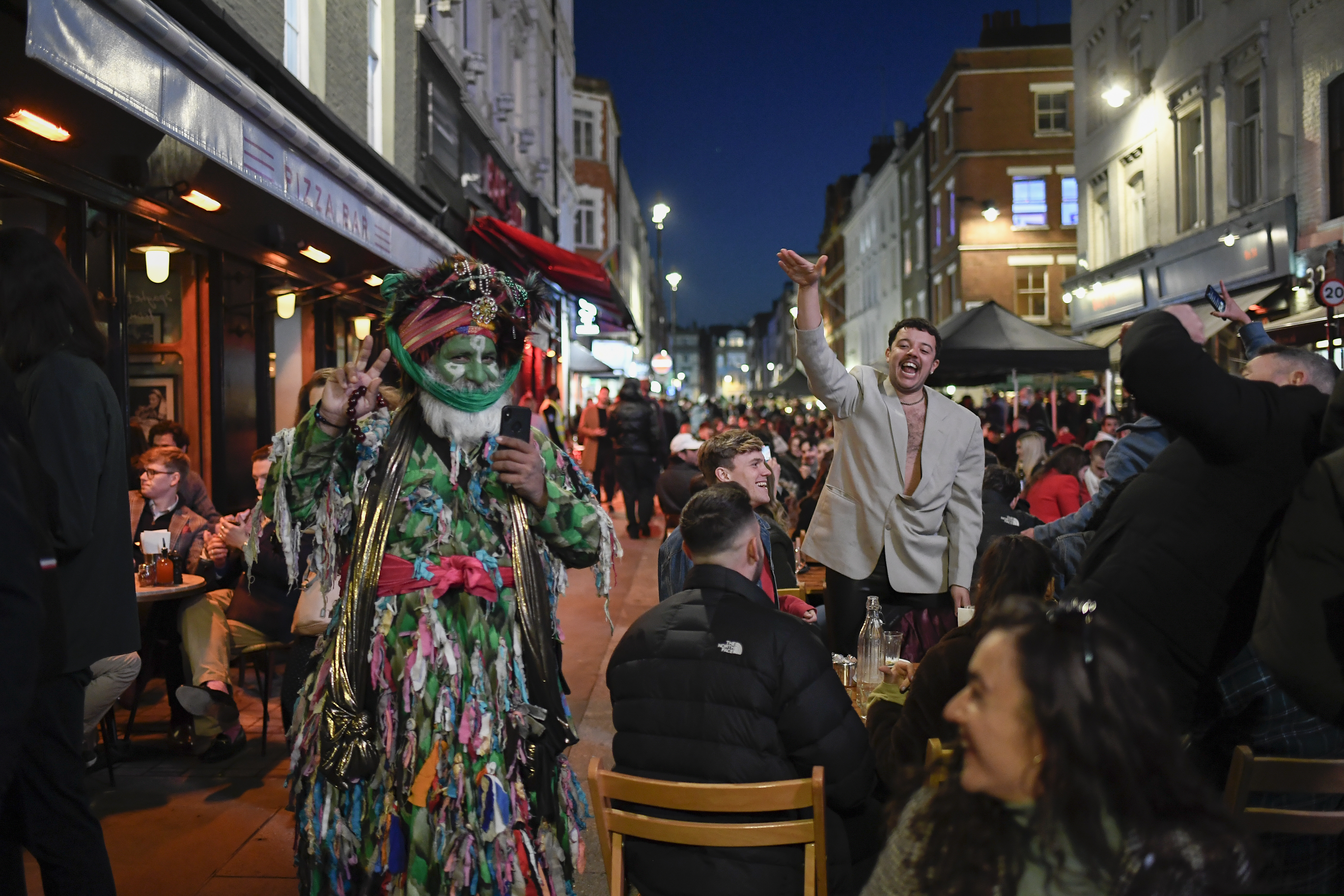 People sit at setup tables outside pubs in Soho, in London, on the day some of England's third coronavirus lockdown restrictions were eased by the British government on Monday. Open Table reservations are one way to track economic activity.