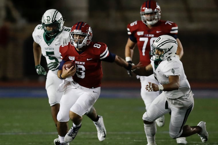 Penn quarterback Nick Robinson runs past Dartmouth linebacker Nigel Alexander (right) and defensive lineman Jackson Perry last weekend.