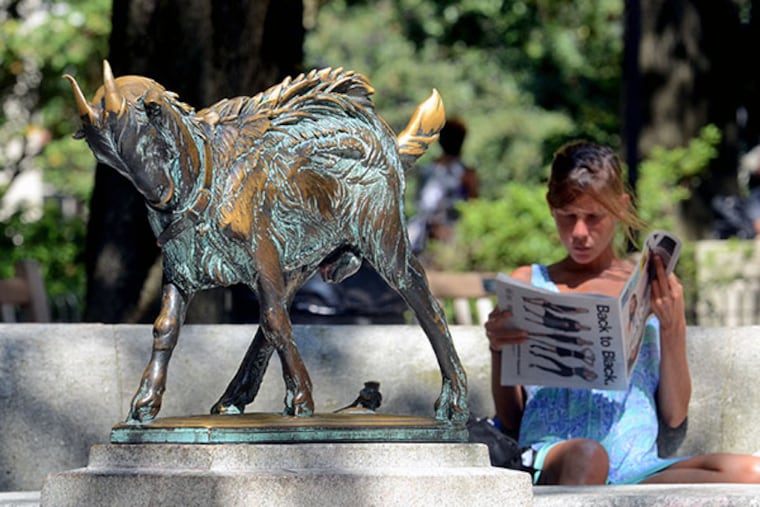 Kate Johnson reads during lunch next to "Billy (1914) by Philadelphia sculptor Albert Laessle (1877�1954) in Rittenhouse Square September 4, 2014. The sculpture was given to the City of Philadelphia by Eli Kirke Price II and was installed in the park in 1919. ( TOM GRALISH / Staff Photographer )