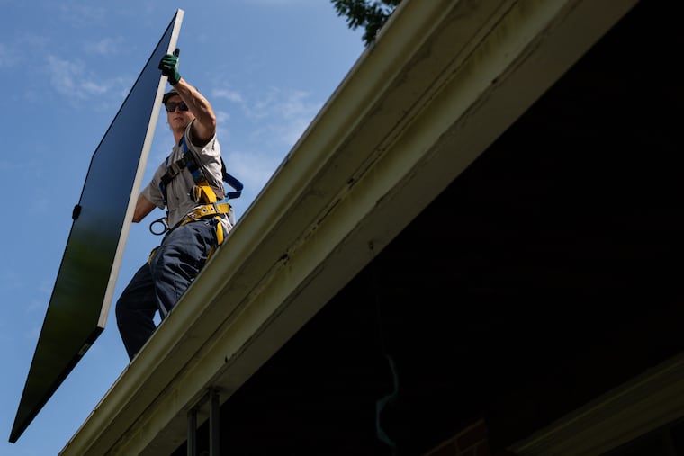 Michael Reimann, an installer with Lumina Solar, adds panels to the roof of a home in Kensington, Md., last summer.