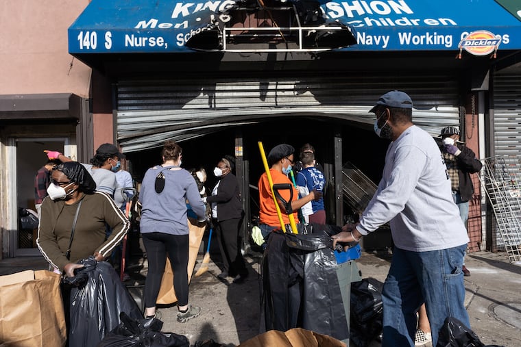 Community members clean up damage and vandalism at a store that was burned out on 52nd Street today in West Philadelphia, June 01, 2020.