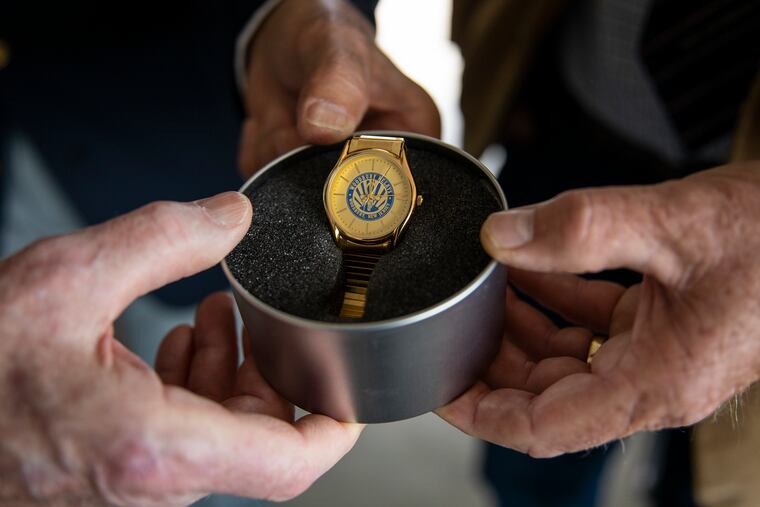Former Woodbury High School athletes Warren Strumpfer, of Blackwood, (Class of 1956), left; Rich Anastasi, of West Deptford, (Class of 1963), center; and Ron Riskie, of Woodbury, ( Class of 1966) hold a gold watch of the kind presented to first-place winners in the annual Woodbury Relays high school track and field event. The late coach Howard V. "Howie" Staeger founded the Relays in 1972.
The track at Woodbury High is being renamed for him.