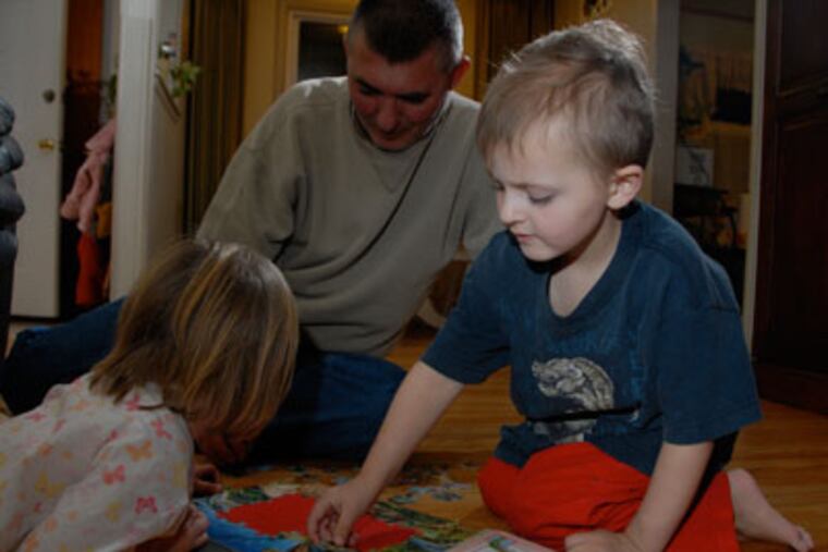 Kyler VanNocker finishes a puzzle with his father Paul VanNocker and sister Anelise in their Edgewater Park, NJ home. (Curt Hudson / For the Daily News)