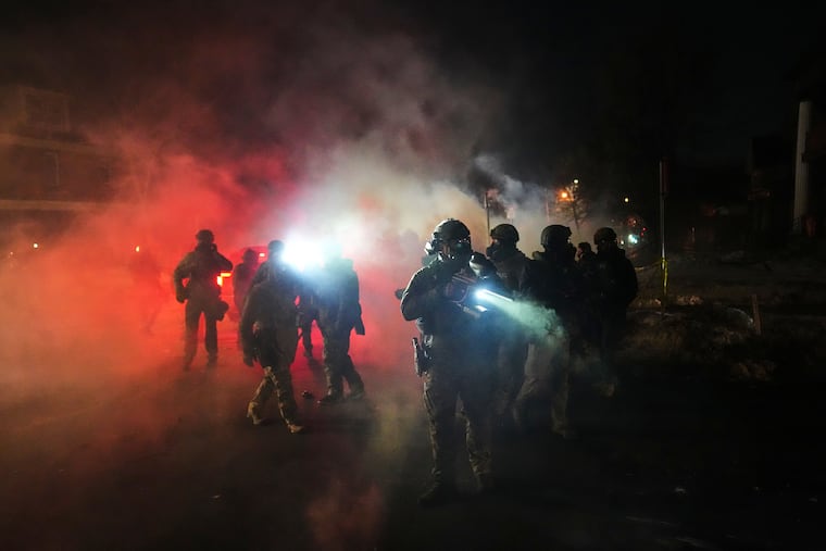 Law enforcement officers stand amid tear gas at the scene of a reported shooting in Minneapolis on Wednesday, Jan. 14.