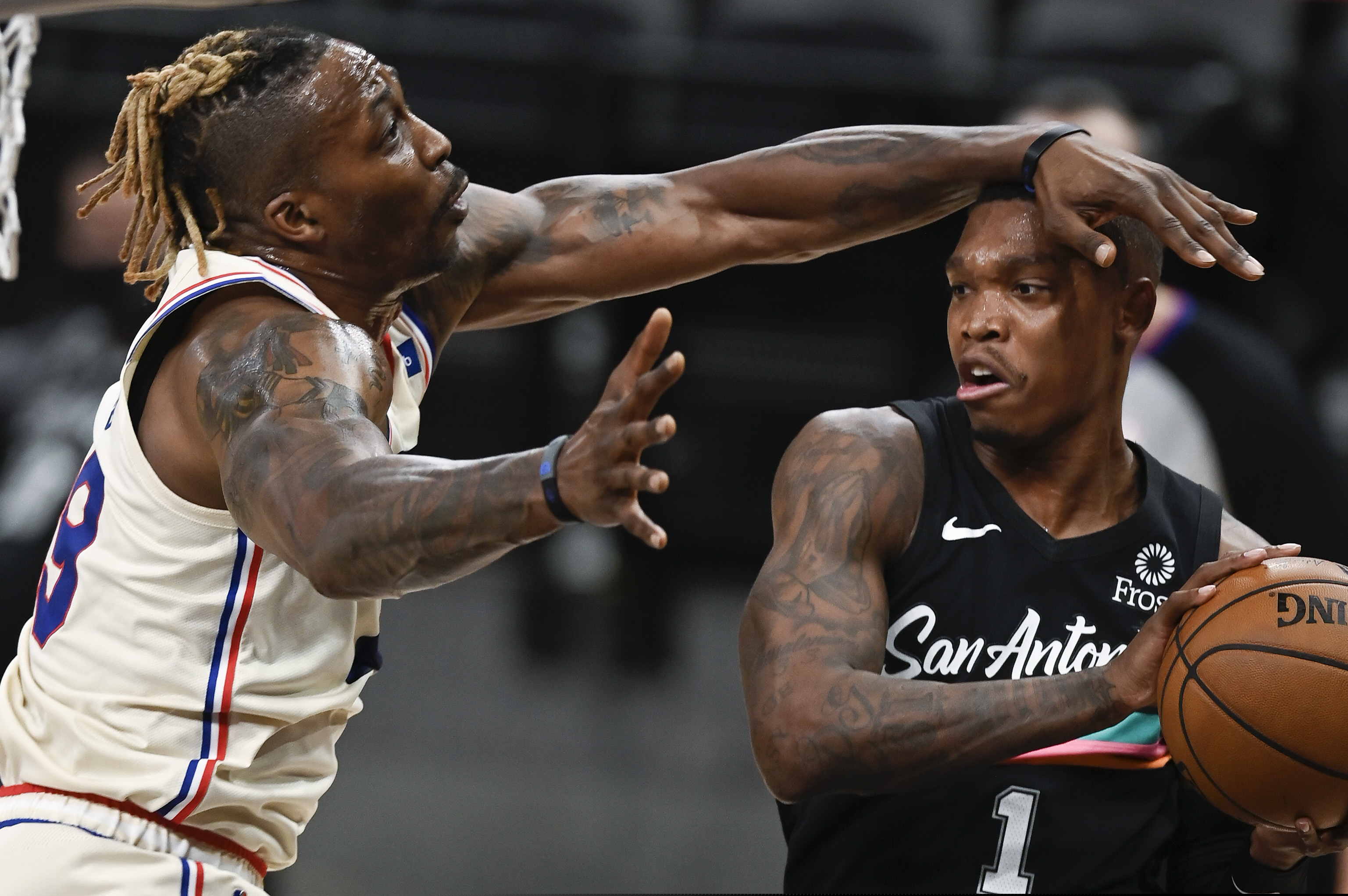 The San Antonio Spurs' Lonnie Walker IV (1) looks to pass as he is defended by the 76ers' Dwight Howard during the first half.