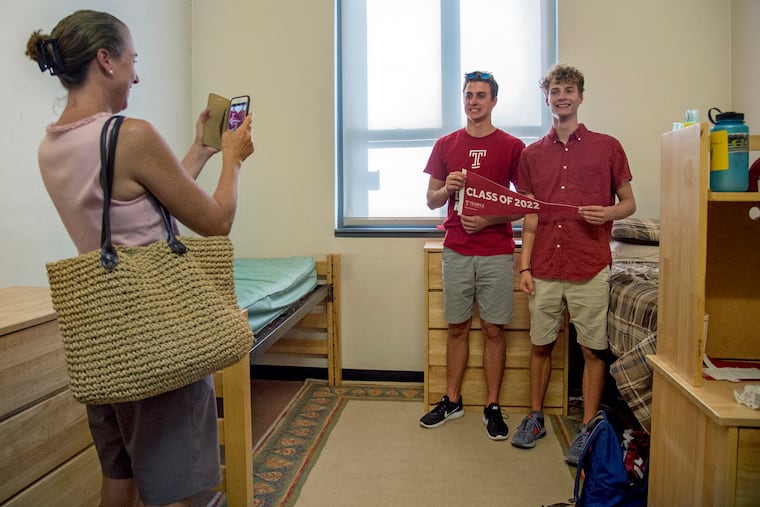 Beth Glennon photographs her freshman sons Seamus (left) and Liam (right) after helping Liam move into his dorm at Temple University on Wednesday. They are two of a set of triplets and counted among 35 sets of twins in Temple's freshman class this year. (Seamus moved into a different dorm the next day).