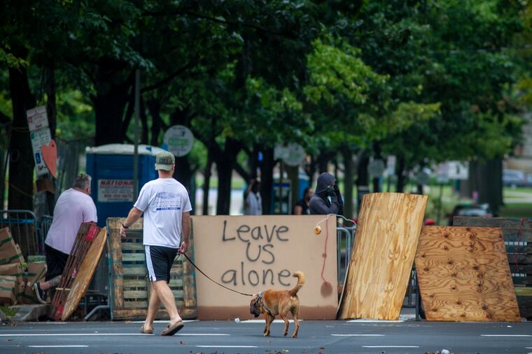 Dog walkers early Thursday morning Sept. 10, 2020, near the homeless encampment at 22nd Street and Ben Franklin Parkway in the Art Museum section of the city.