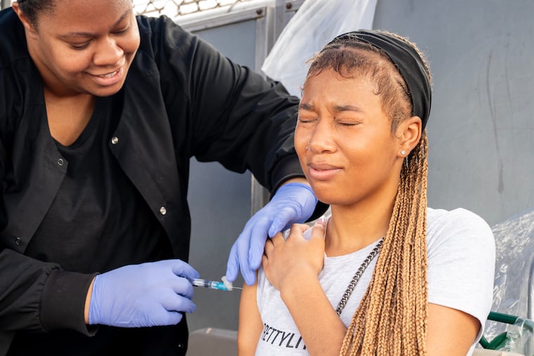 Clinical superviser Wyntre Jackson gives an immunization to Cianey Brown, 16, at a vaccination clinic this month during the School District of Philadelphia’s sixth annual Back-To-School Bus Tour stop at Marcus Foster Memorial Stadium.
