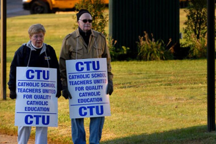 Camden Catholic High School teachers Vicki Trainor, left, and John Oakes picket outside the school as students arrive for classes this morning. (TOM GRALISH / Staff Photographer)