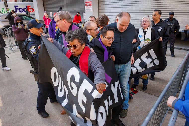 Clergy members get pushed away from the garage door at ICE headquarters during Monday's protest.