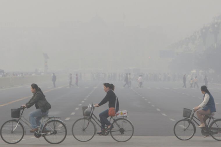 Chinese women cycle through a brown cloud of smog and pollution in Beijing's Tiananmen Square. These clouds hide the sun, absorb radiation.