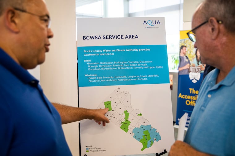 Larry Woodson (left), of Plumstead Township, and Brian Haley, of Richland Township, talk over one of the signs displayed by Aqua America during an open house held by Bucks County Water and Sewer Authority in Perkasie in 2022.