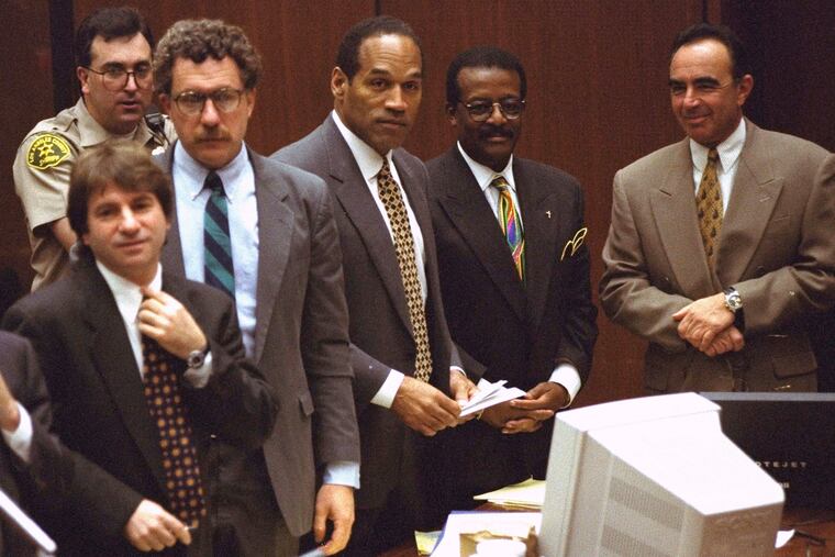 Defendant O.J. Simpson and members of his defense team react as the jury, many wearing white T-shirts sporting a slogan from a local pizza chain, walk into the courtroom in Los Angeles on May 5, 1995.