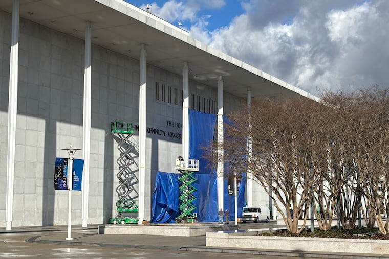 Construction workers install new signage on the Kennedy Center on Friday.