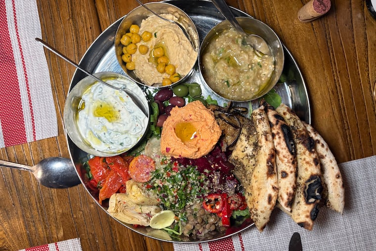 The hummus is one of the highlights of the mezze platter at Stina, where the chickpea puree is blended with the sweetness of roasted garlic, topped with crispy chickpeas, and served with the restaurant's wood fire-baked pitas.