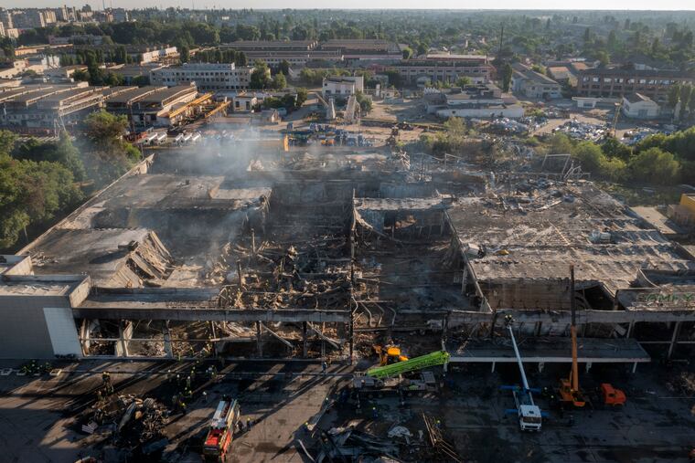 Ukrainian State Emergency Service firefighters work to take away debris at a shopping center burned after a rocket attack in Kremenchuk, Ukraine, on Tuesday.