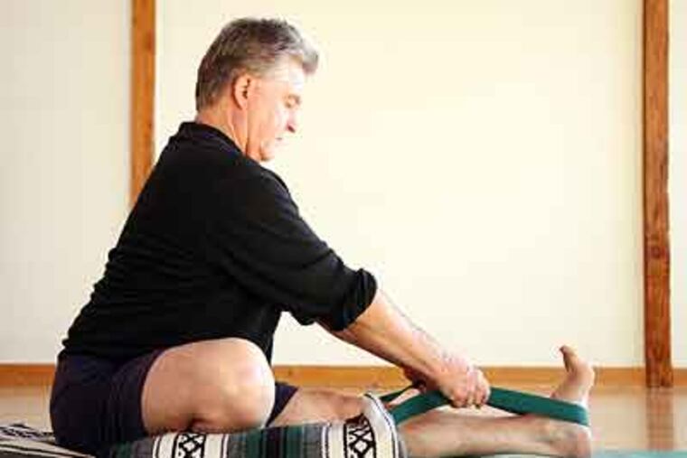 Tony Briggs, director and owner of Turtle Island Yoga, demonstrates the correct way to do a stretch, stressing the use of the supplemental equipment that is meant to help prevent injury. (Laura A. Oda / Oakland Tribune / MCT)